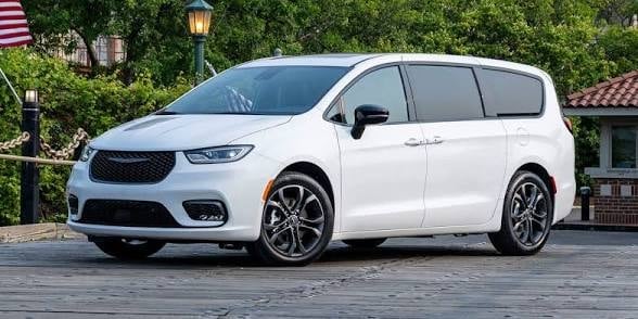 White minivan with dark grille parked on stone driveway with residential background